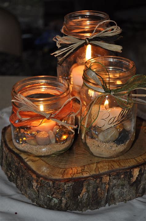 Three Mason Jars Filled With Sand And Lit Candles On Top Of A Wooden