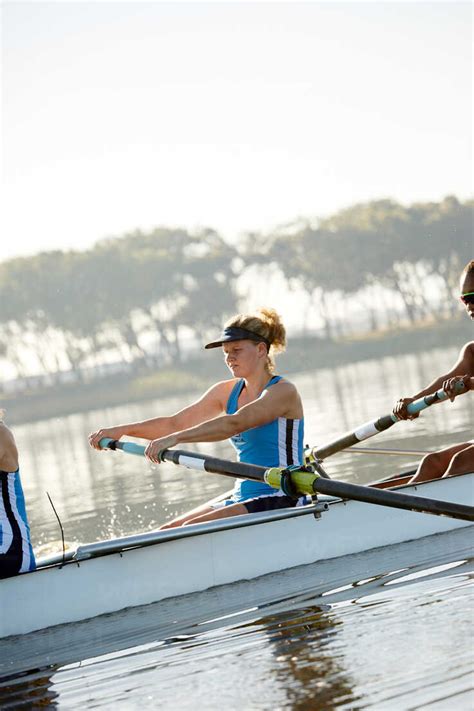 Determined Female Rower Rowing Scull On Lake Stock Photo