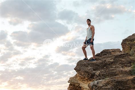 Young Casual Man Standing On The Mountain Rock By The Sea And Looking