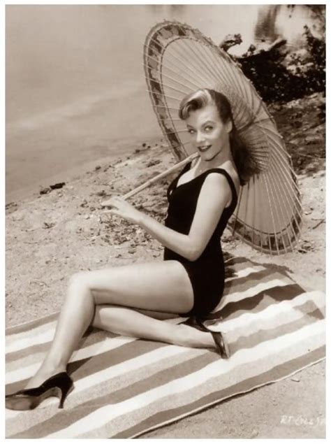 A Woman In A Bathing Suit Sitting On A Towel With An Umbrella Over Her Head