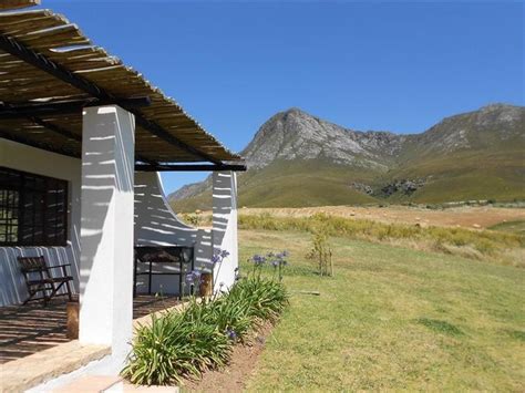 The Outside Of A House With Mountains In The Backgroung And Grass On