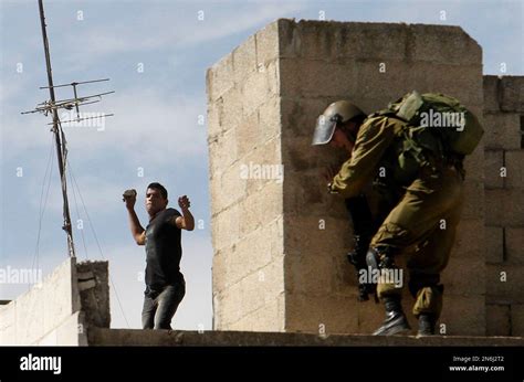A Palestinian Man Throws A Stone Towards An Israeli Soldier During