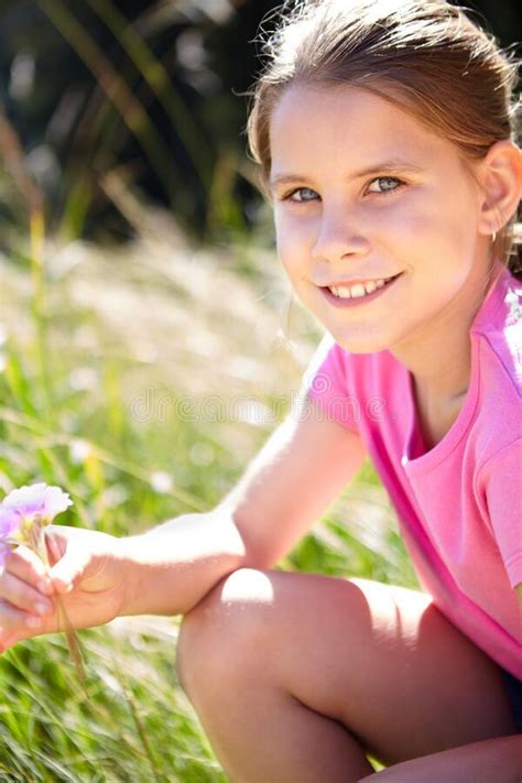 Pretty Great Summer Portrait Of A Young Girl Holding A Flower While Sitting In A Field Stock