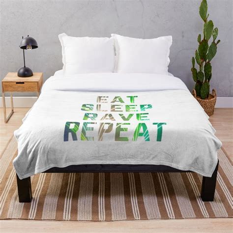 A Bed With A Blanket That Says Eat Sleep Rave Repeat