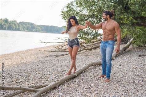 Couple In Love On The Beach Of Danube River Balancing Over A Tree Bearded Topless Guy With Long