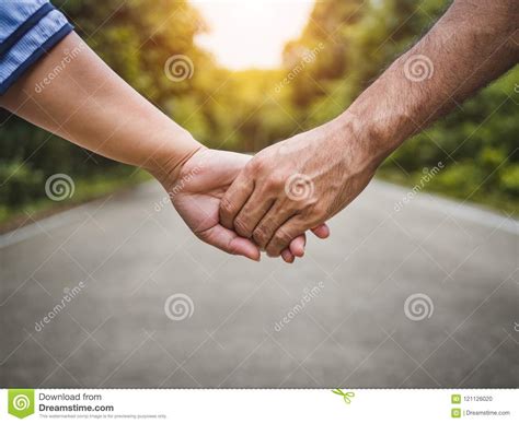 Couple Holding Hands On The Road And Forest Blurred Background Stock