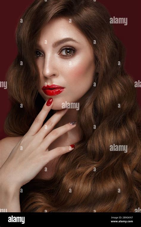 beautiful girl with a classic make up curls hair and red nails manicure design beauty face