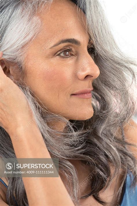 A Middle Aged Woman With Grey Hair Pulls Her Hair Behind Her Ear Superstock