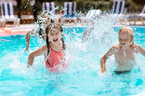 Niños Que Ríen Mientras Que Salpica El Agua En Piscina Imagen de archivo Imagen de piscina