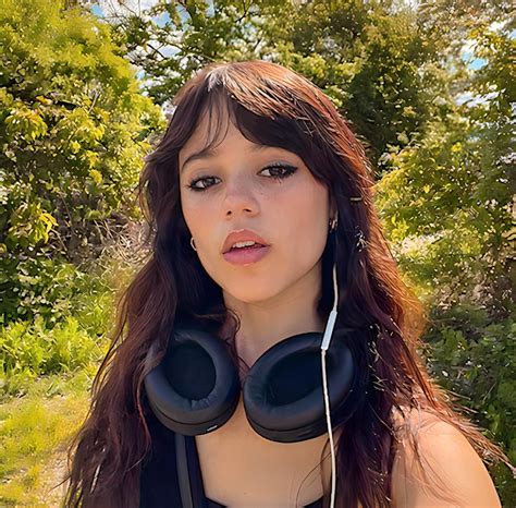 a woman wearing headphones standing in the woods