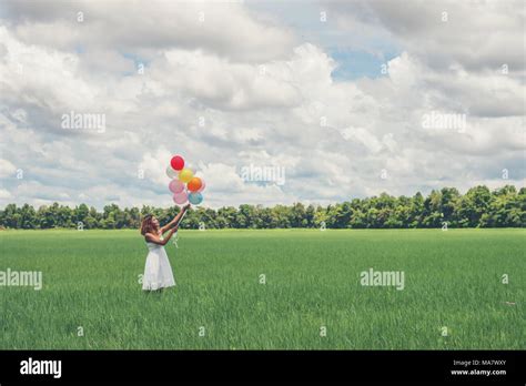 Happy Young Beautiful Woman Holding Balloons In The Grass Field Enjoy