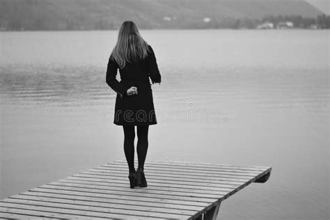 The Lonely Woman Looks At The Lake Sadly In Winter Stock Photo Image