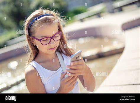 Une Jeune Fille Blonde Pr Adolescente Regarde Dans Le T L Phone Portable Dans Sa Main Assise
