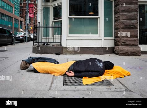 Homeless Man Sleeping On The Sidewalk Covered With Blanket In Downtown