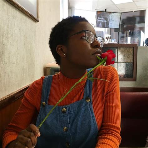 A Woman Sitting At A Table With A Rose In Her Mouth