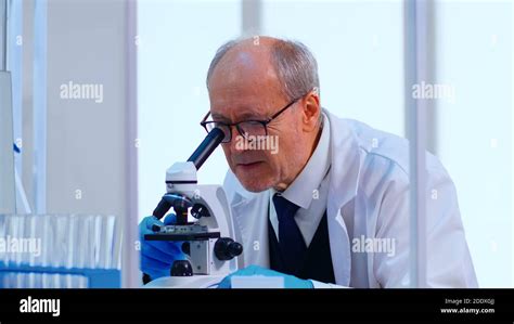 técnico superior de laboratorio que examina muestras y líquidos mediante microscopio en un