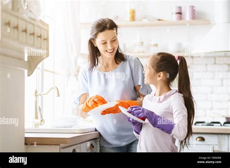 Helping Hand Cute Teenage Girl Helping Her Mother In Washing Dishes At