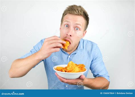 Young Handsome Man Eats Chips With Paprika From Plate On Isolated White