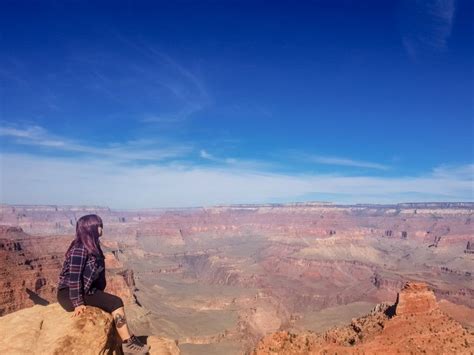 Girl Sitting On Edge Of Grand Canyon At Ooh Ahh Point Looking Out Over