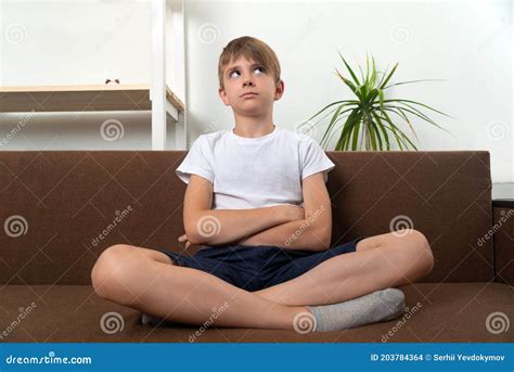 Pensive Guy Sitting On The Couch Arms Crossed And Legs Folded In Lotus