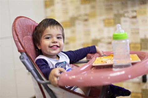 Portrait Of Happy Little Boy Sitting On High Chair Stock Photo