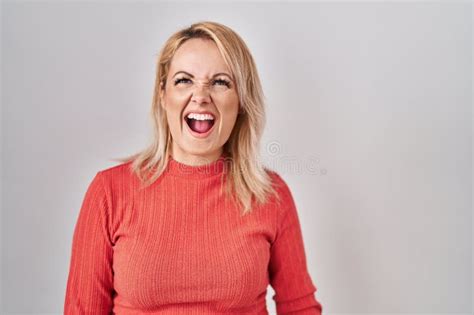blonde woman standing over isolated background angry and mad screaming frustrated and furious
