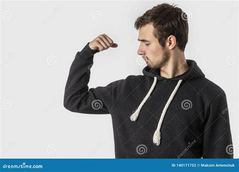 Weak Caucasian Young Man Looks At His Biceps Disappointedly Isolated
