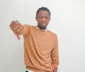 Jeune homme africain ayant un regard triste et son pouce baissé sur un fond blanc Photo