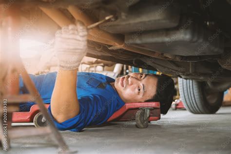 Auto Mechanic Working Under A Car Mechanic Lying And Repairing Under