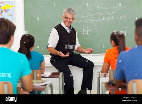 Friendly Male Teacher Explaining Lesson To Students In Classroom Stock
