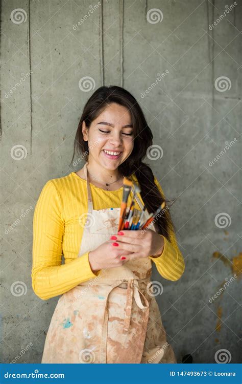 Young Beautiful Lady Artist In Apron With Paint Stains In Her Loft