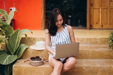 mulher asiática trabalhando no laptop em um período de férias e sentado nas escadas foto grátis