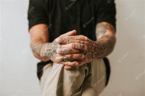 Premium Photo Tattooed Man With Hands Clasping His Knees