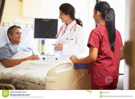 Female Doctor Talking To Male Patient In Hospital Room Stock Photo