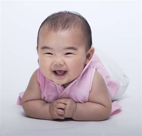 Portrait Of Smiling And Laughing Baby Lying Down Studio Shot White