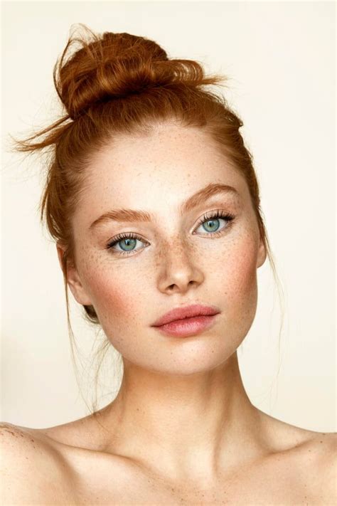 a woman with freckled hair and blue eyes is posing for the camera while wearing a topknot
