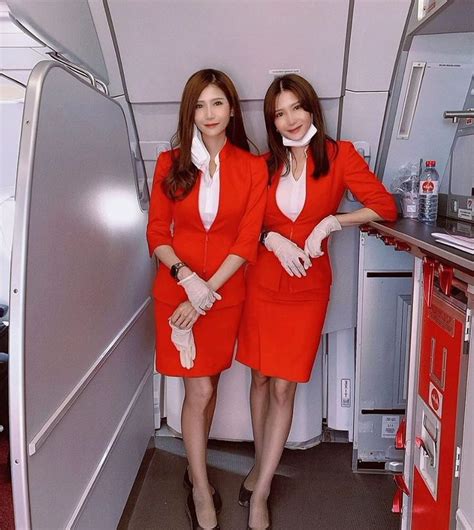 two women in red uniforms standing next to each other on an airplane with the door open