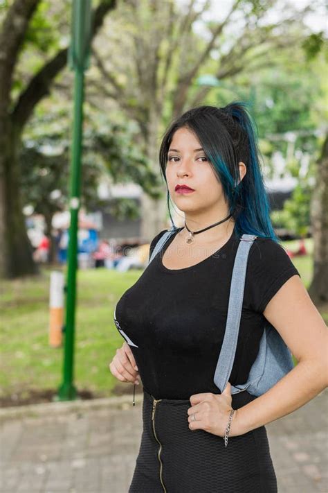 Latin College Girl With Blue Hair Walking Through The Park Dressed In Black And Blue Bag