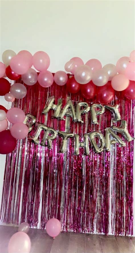A Pink And White Birthday Party With Balloons Streamers And Tassels On