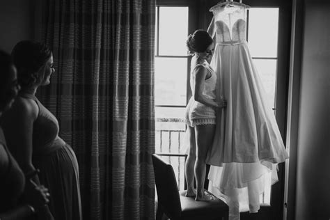 A Bride Admiring Her Wedding Dress In Front Of A Window At Alfond Inn Susan Stripling Photography