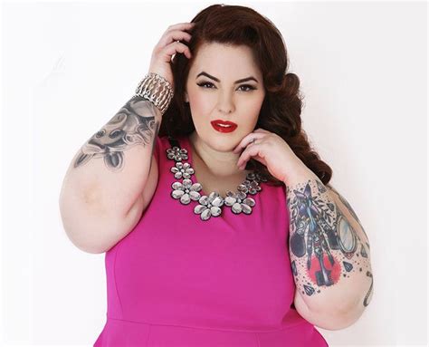 a woman in a pink dress with tattoos on her arm and arms behind her head