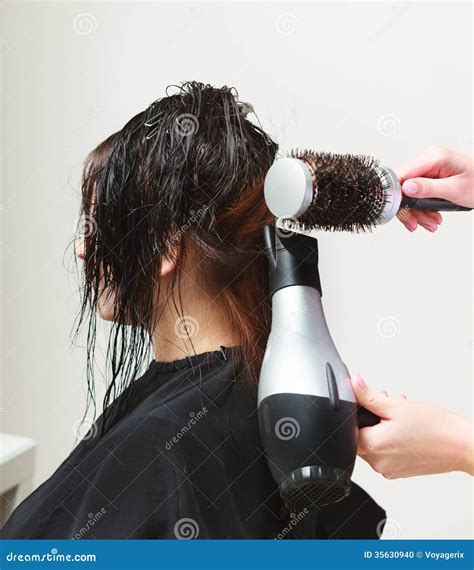 In Hairdressing Salon Hairstylist With Dryer Drying Hair Of Woman