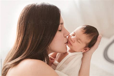 Loving Mother Kissing Her Newborn Baby S Cheek By Stocksy Contributor