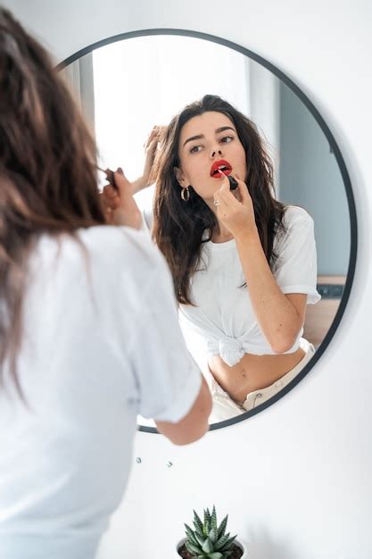 Free Photo Young Woman Applying Lipstick Looking At Mirror