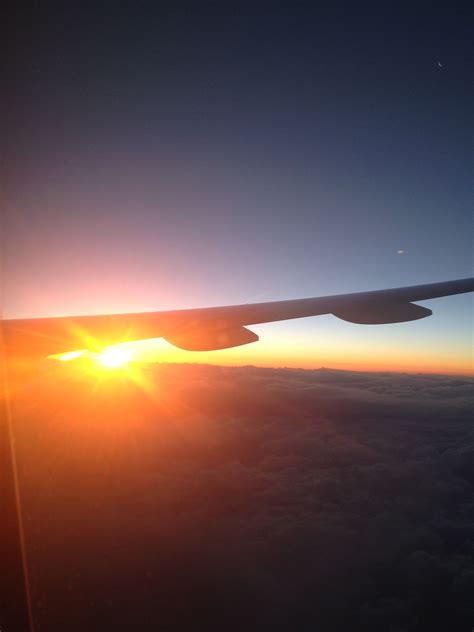 Photograph From A Plane Window Of The Sunrise Over The Clouds Above The