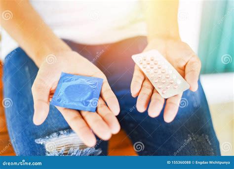 woman holding contraception pills and condom in hand birth control contraceptive means prevent