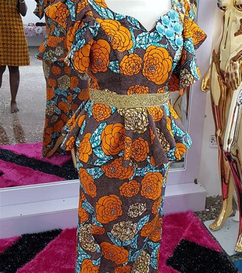 A Mannequin Dressed In An Orange And Blue Floral Print Dress With Gold Belt