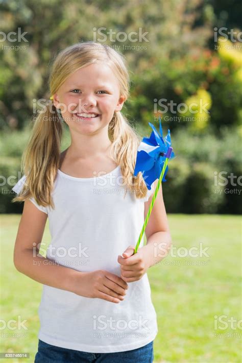 Blonde Girl Smiling And Holding Pinwheel Stock Photo Download Image