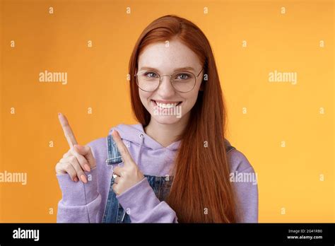 Confident Good Looking Sassy Smiling Redhead Freelancer Girl Wearing Glasses Pointing Upper Left