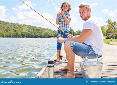 Father And Son Are Fishing Together At The Lake Stock Photo Image Of